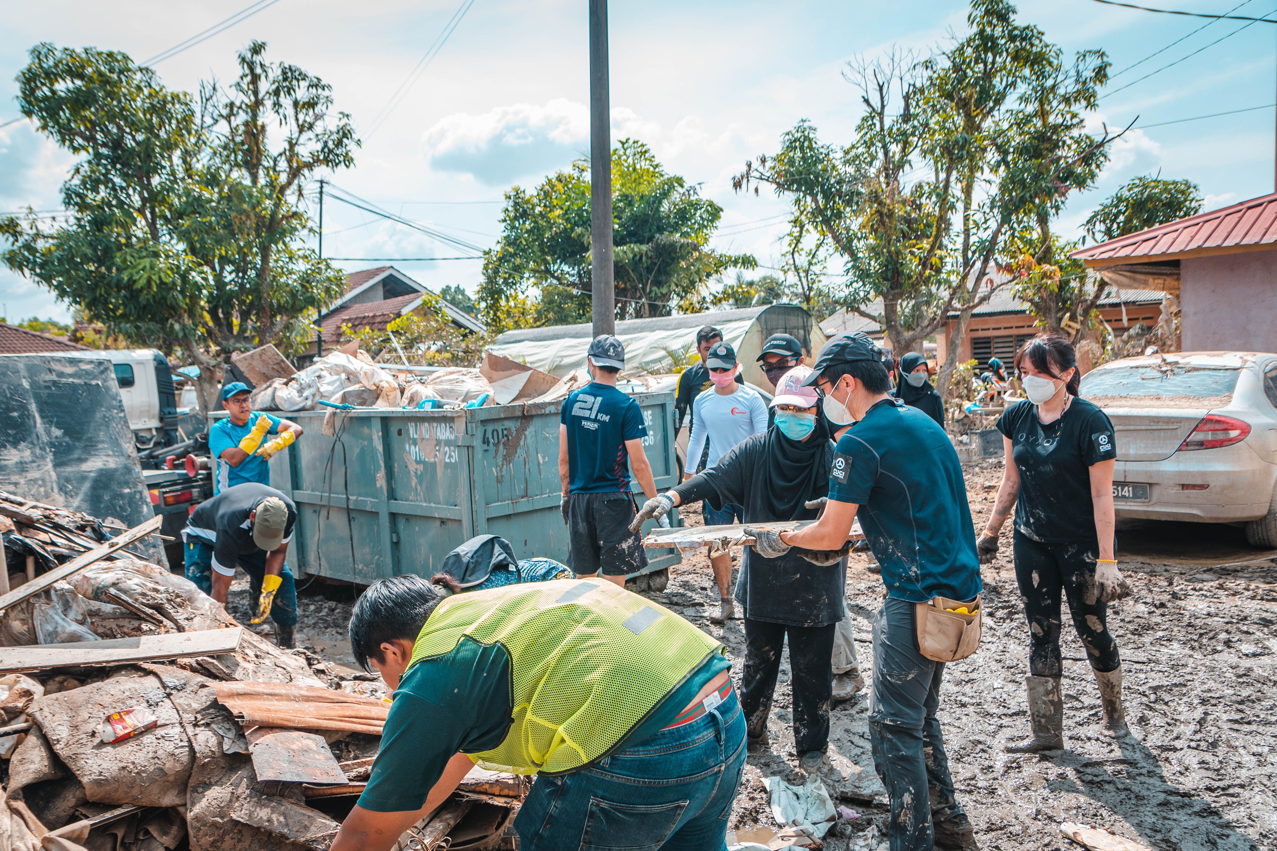Volunteers cleaning up debris together after a natural disaster, showing community recovery