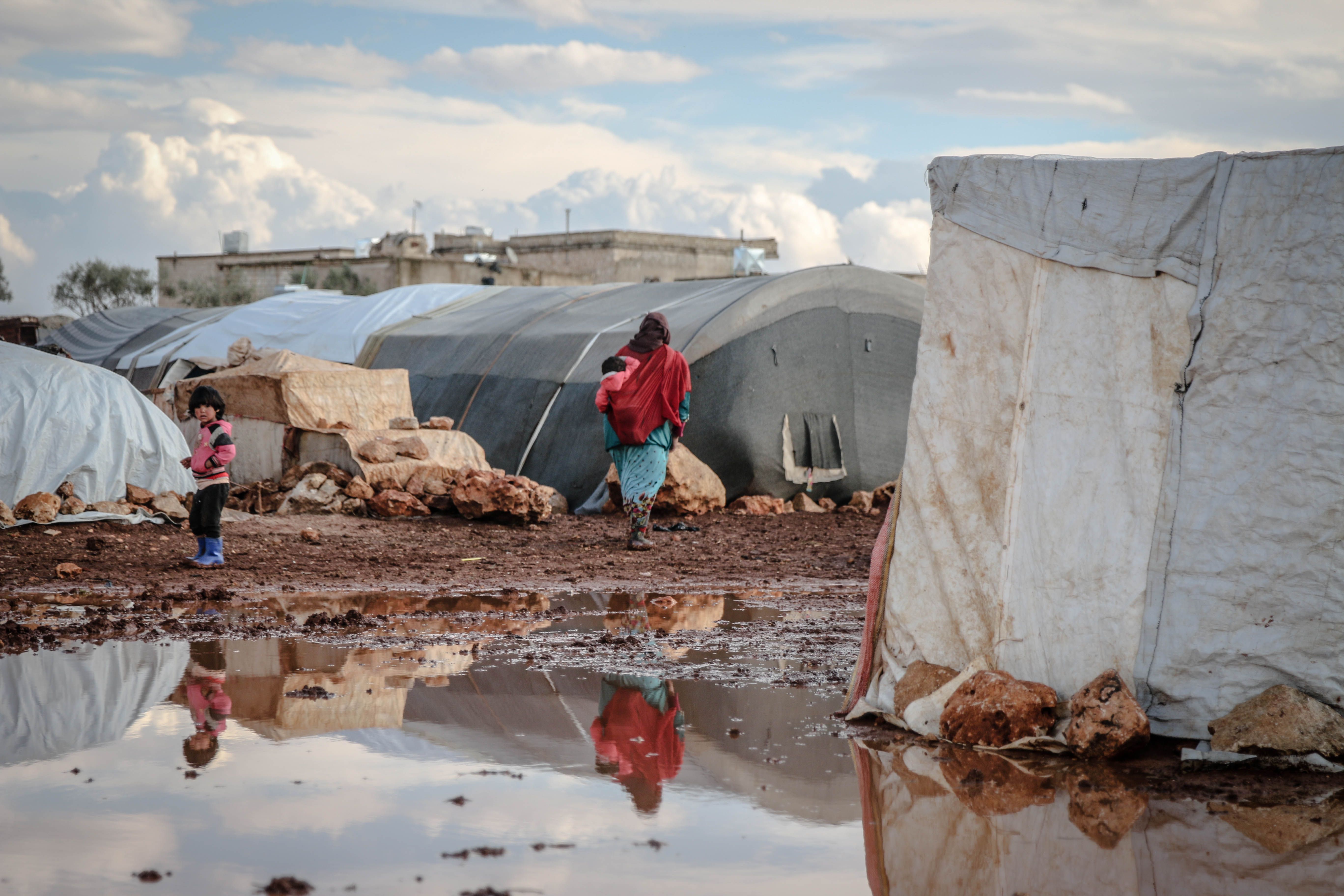 A tent camp for displaced families struggling in muddy conditions after losing their homes