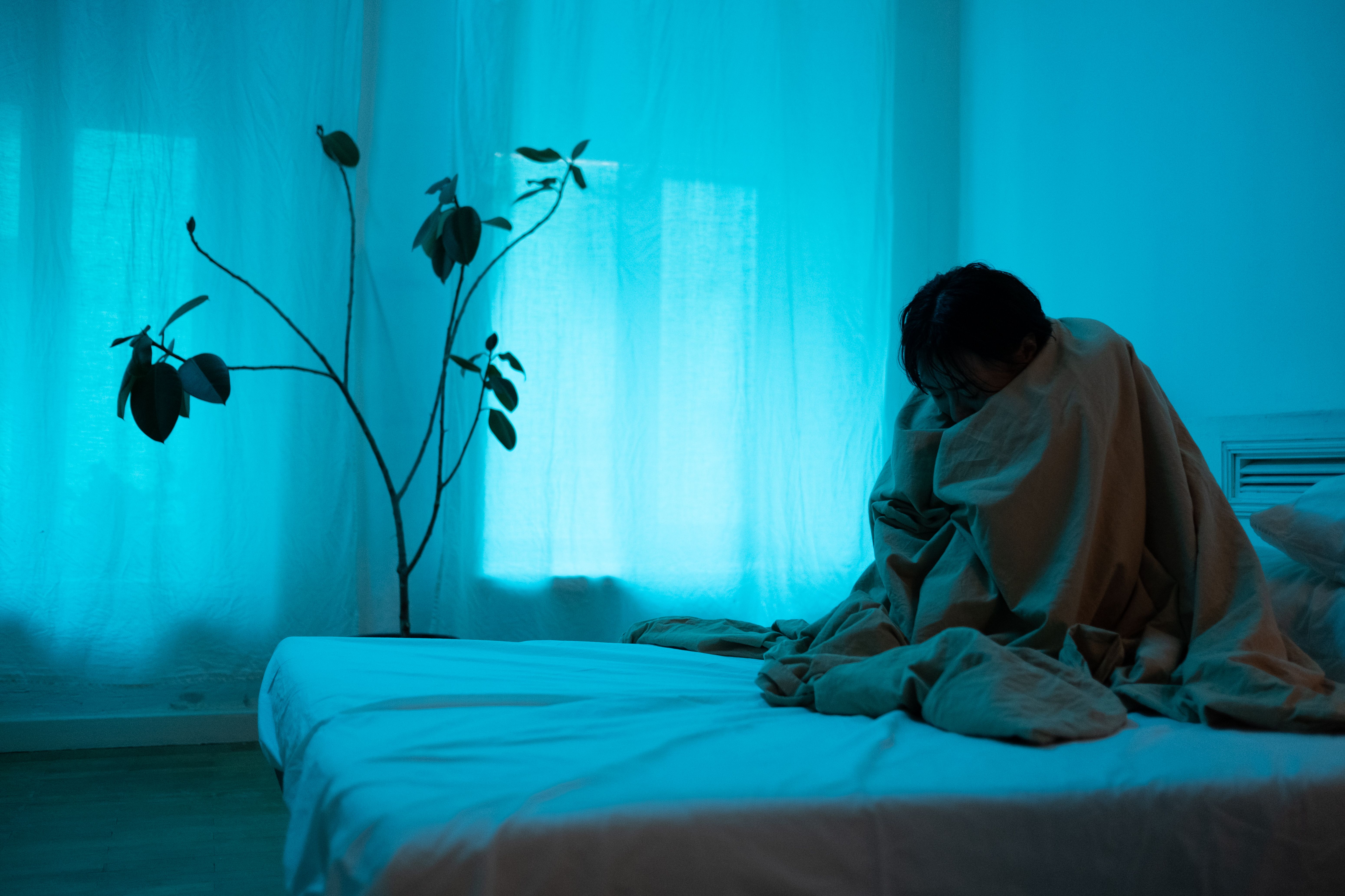 A woman sitting alone wrapped in a blanket, expressing loneliness and depression after displacement