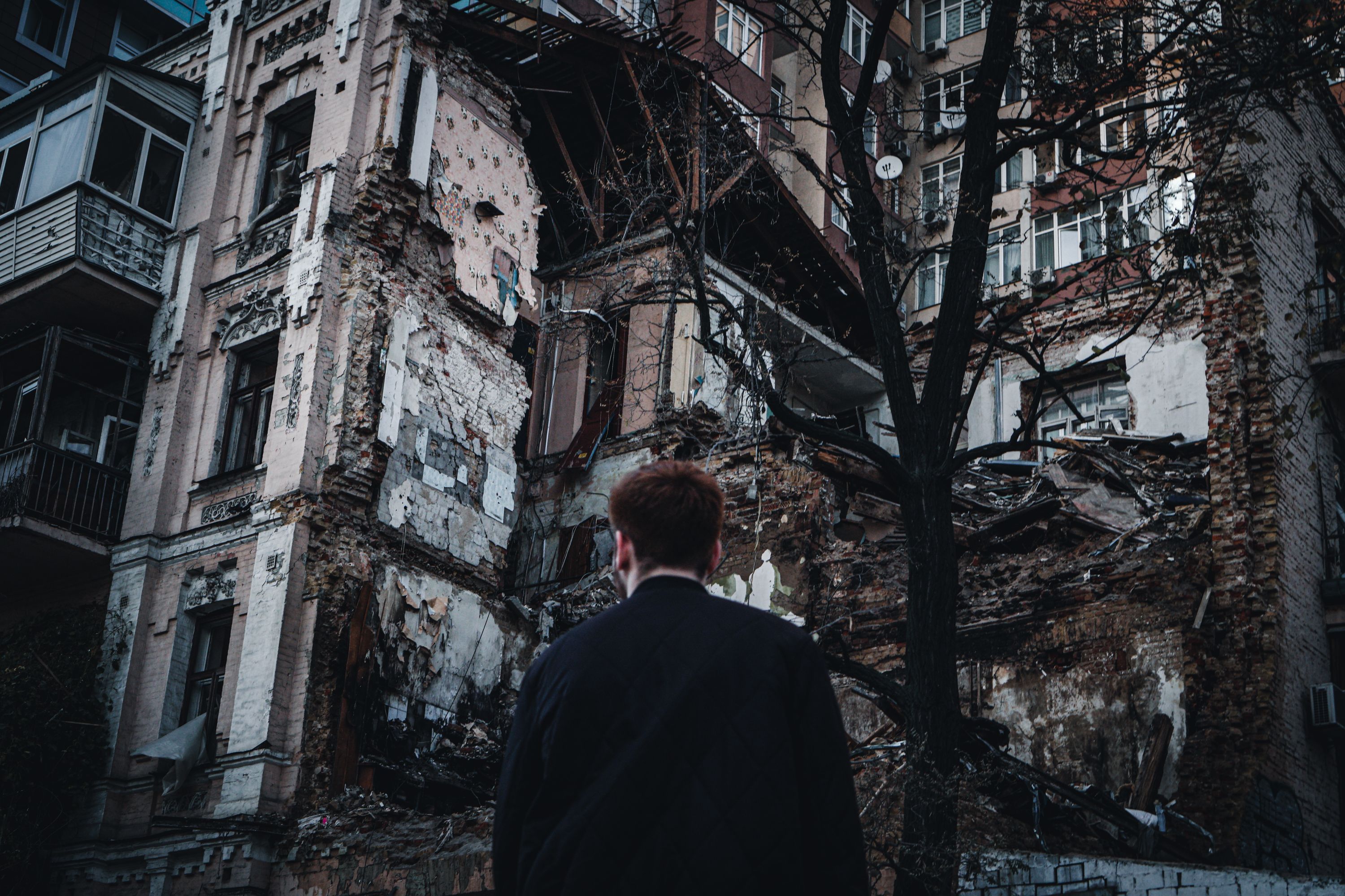 A man looking at a damaged residential building after a disaster