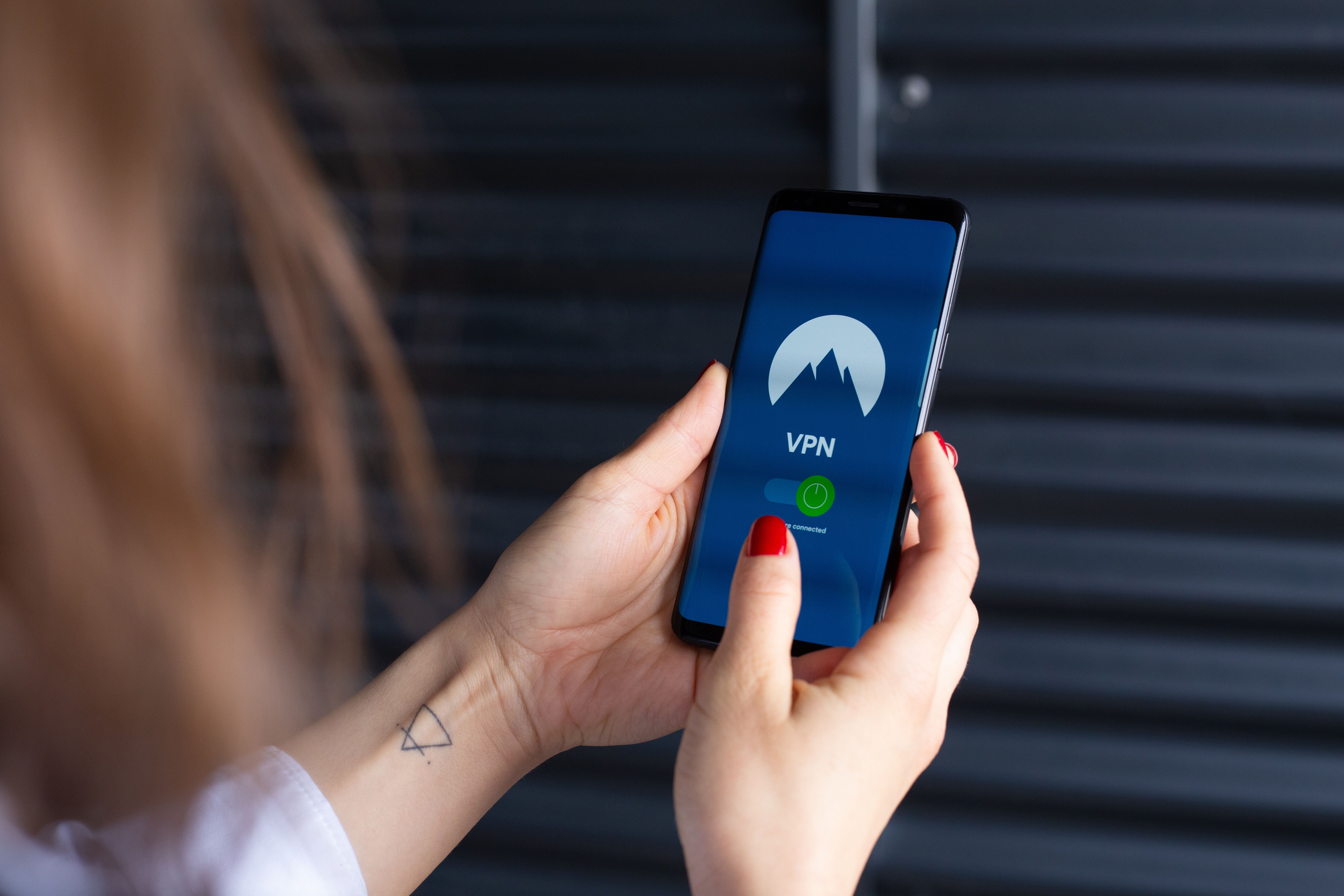 Woman's hands using a VPN app on a smartphone, emphasizing digital privacy and security tools