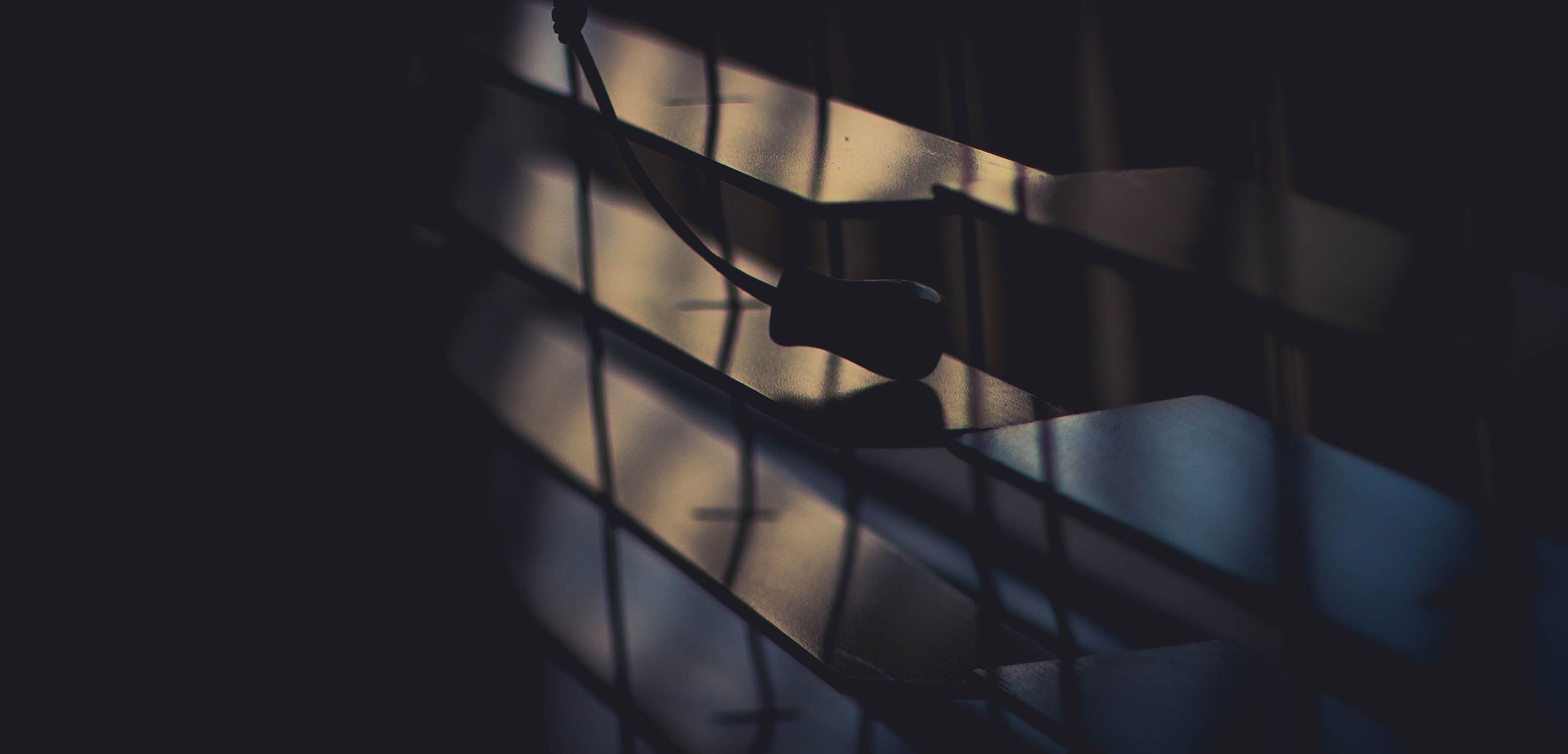 Dramatic close-up of window blinds casting a silhouette in soft lighting, symbolizing privacy from prying eyes