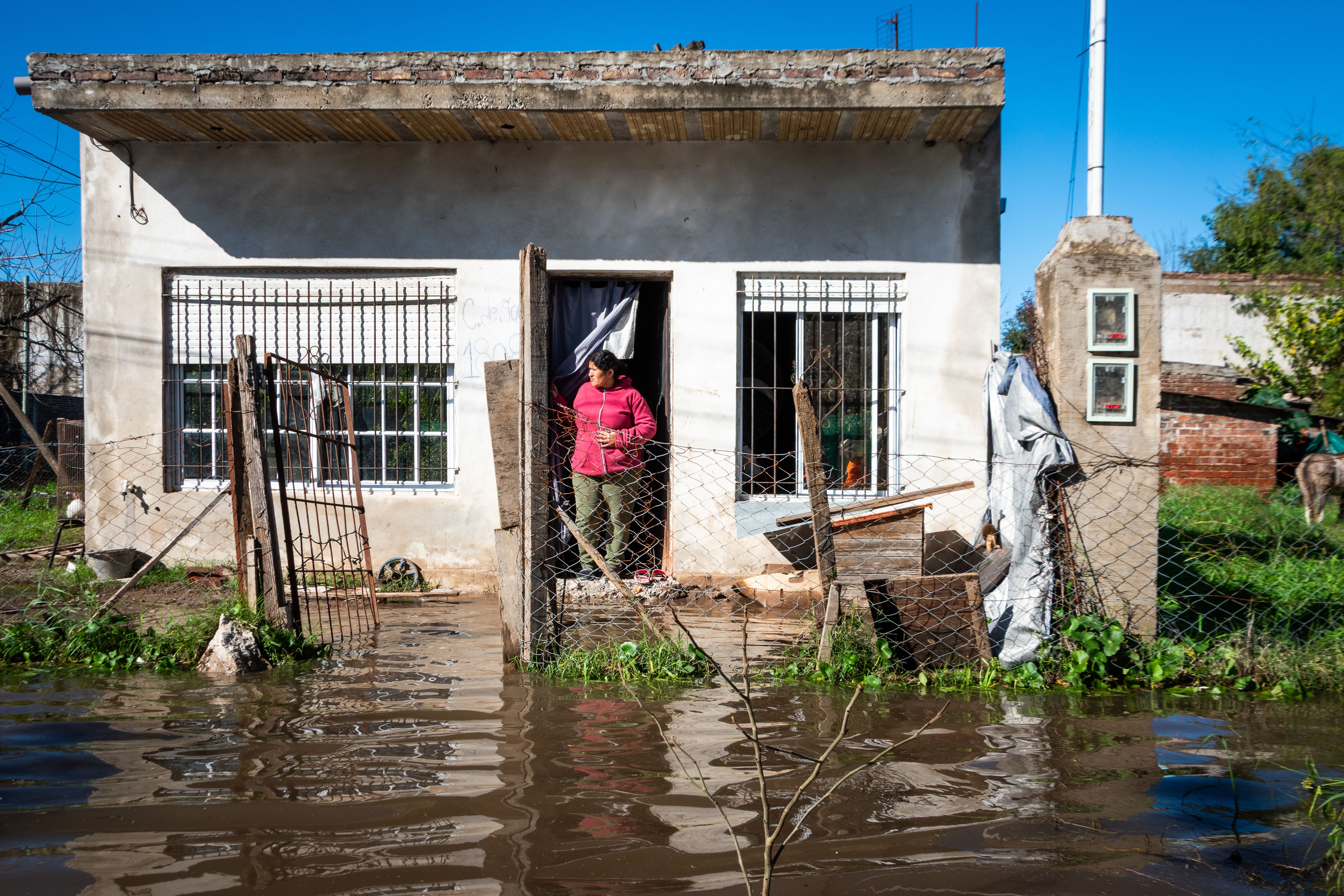 A woman standing at the entrance of her flooded home after a disaster