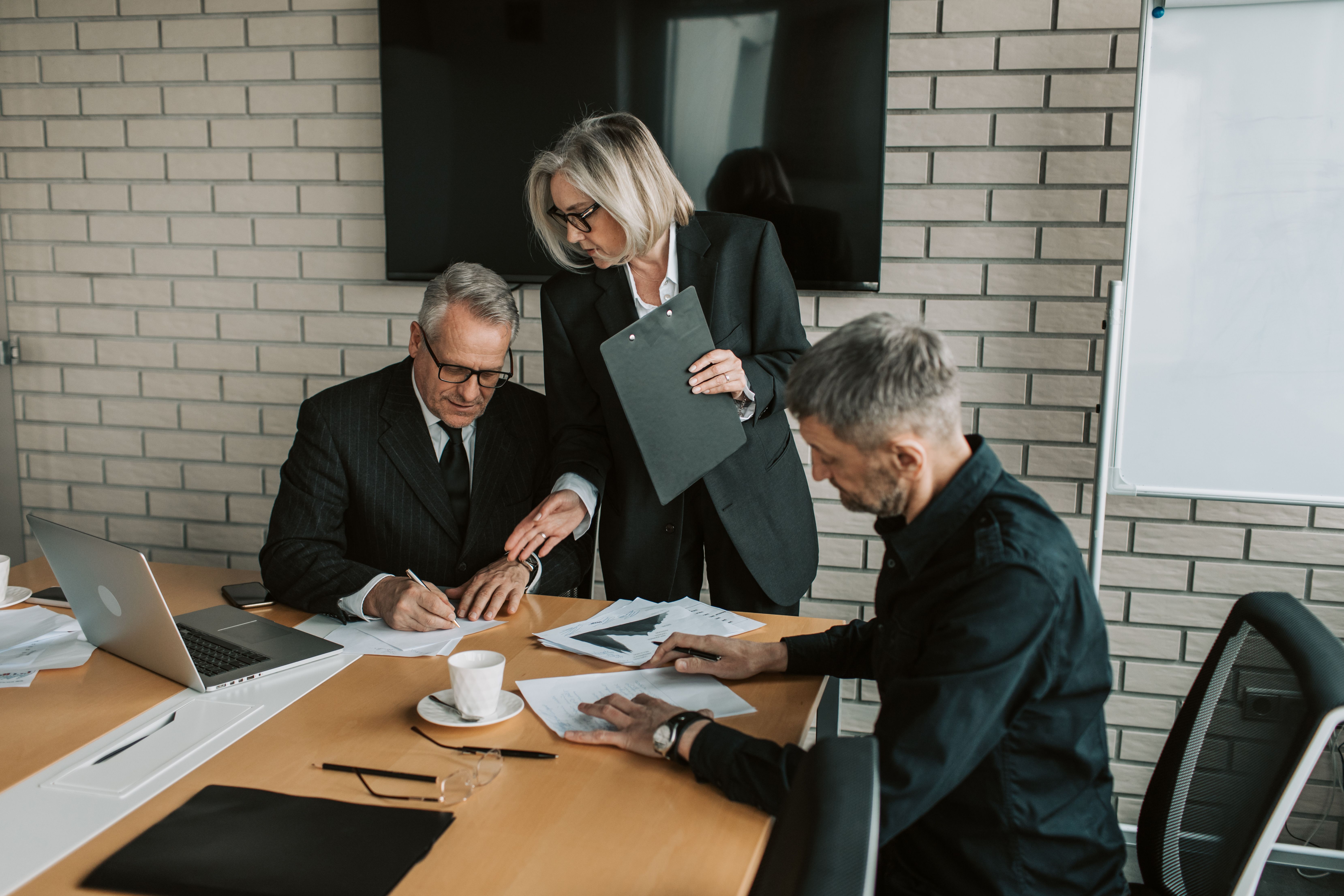 Three professionals in a business meeting discussing and signing documents